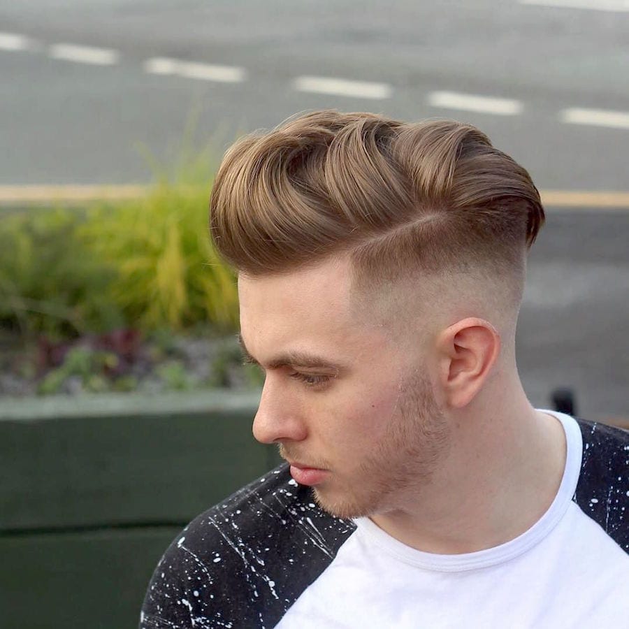 A boy in black and white t-shirt showing the side view of her Skin Fade with Half Hard Part - hairstyles for men and boys