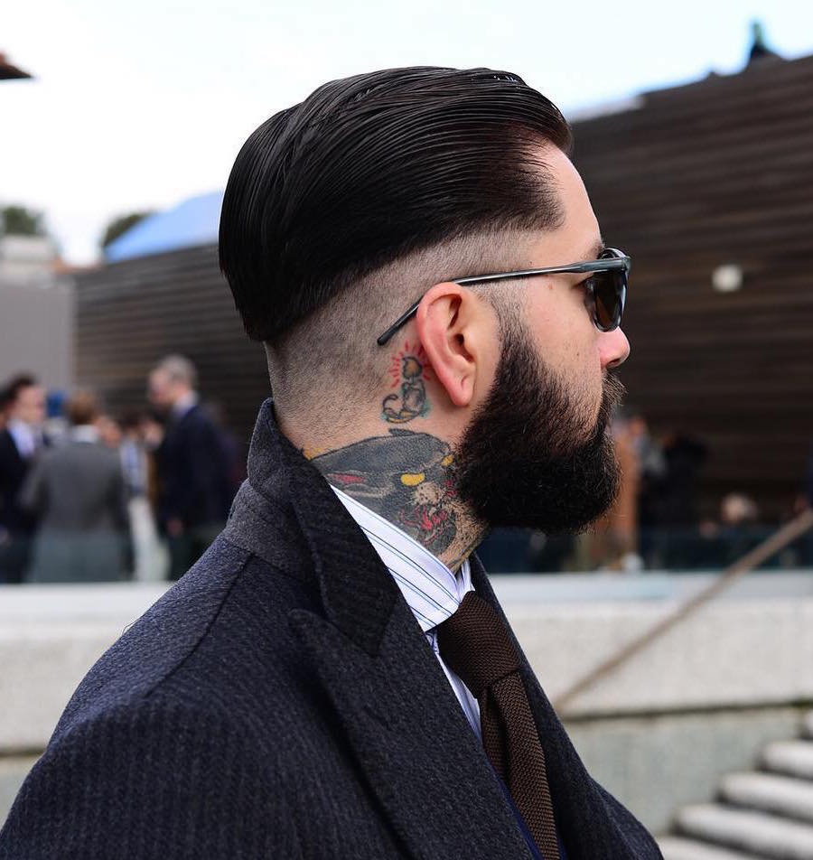A man, with tattoos on his neck,  in black coat with white lining shirt and tie along with goggles - Latest Hair Cut for Men and Boys