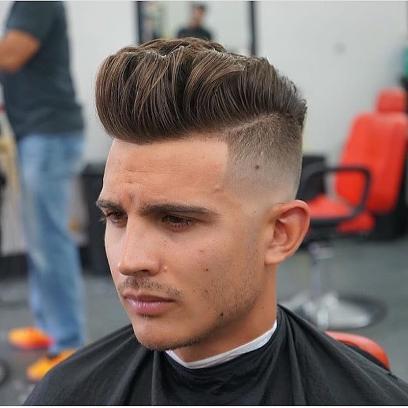 A sitting on a chair and showing his High Fade Pompadour hairstyle - Latest Hair Cut for Men and Boys