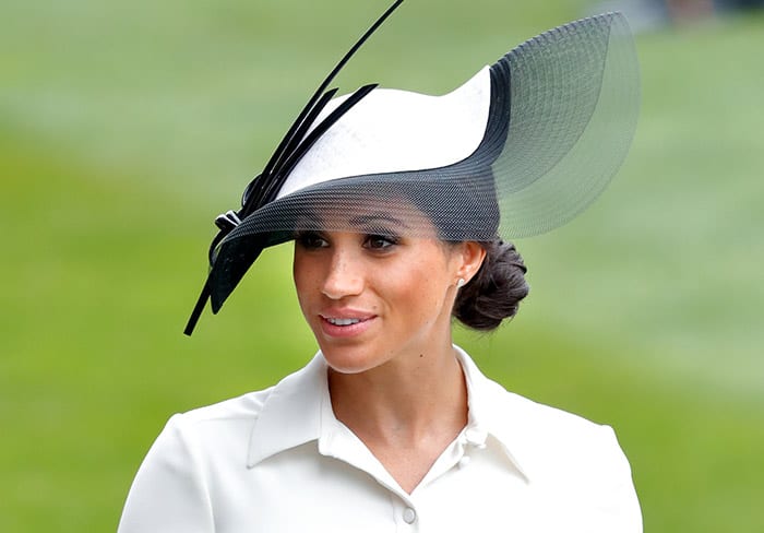 Meghan Markle with a black hat and bun hairstyle