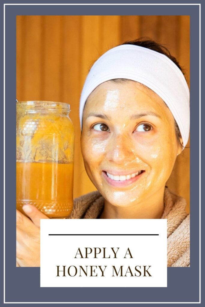 A girl has applied honey mask on her face and showing the honey jar - tips glowing skin