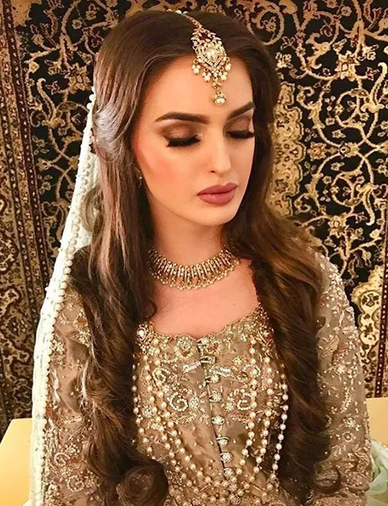 A girl in golden and white traditional attire showing her Center Parted Curls A girl in golden and white traditional attire showing her Center Parted Curls - hairstyles for Indian Wedding