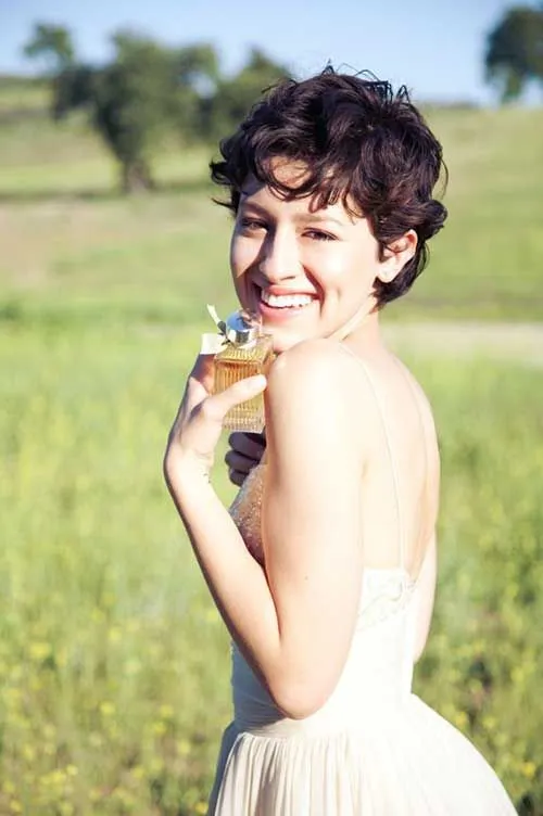 A smiling girl in multicolor deep neck top showing her curly pixie with bangs A smiling girl in multicolor deep neck top showing her curly pixie with bangs - haircut Teenage Girls