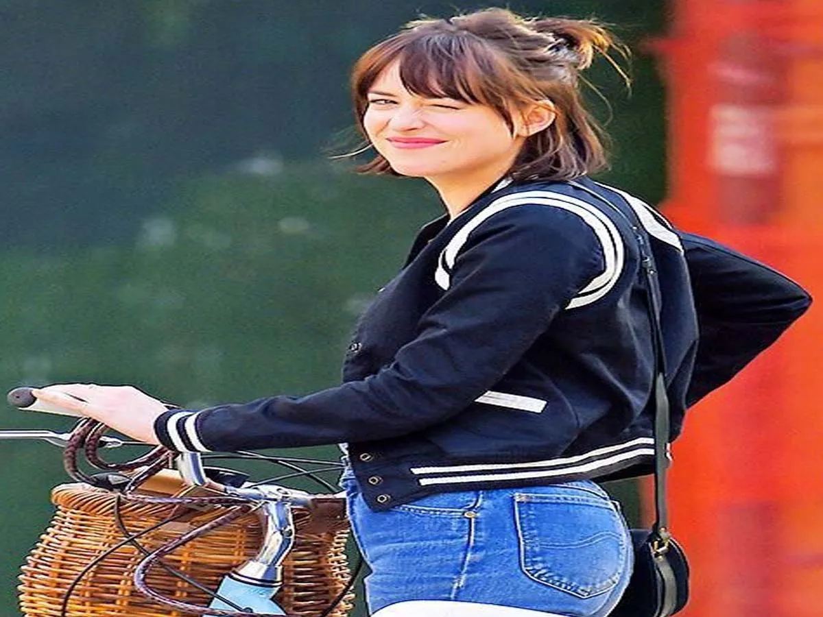 Dacota Johnson in light blue jeans with navy blue jacket riding a cycle - celebrity short hair cuts