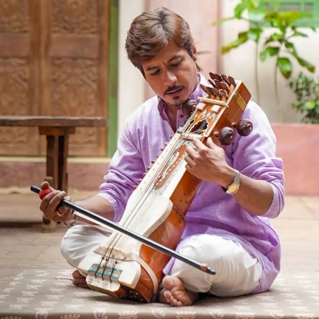 Amit Mistry posing with a musical instrument in his hand - celebrity death of 2021 