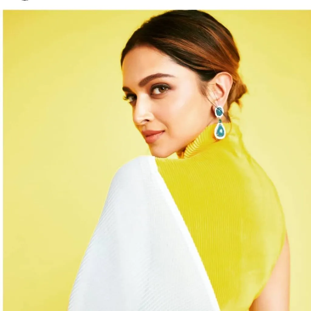 Deepika Padukone in white sari and yellow blouse smiling and giving side pose with ballerina bun Deepika Padukone in white sari and yellow blouse smiling and giving side pose with ballerina bun - Deepika Padukone hairstyles with saree