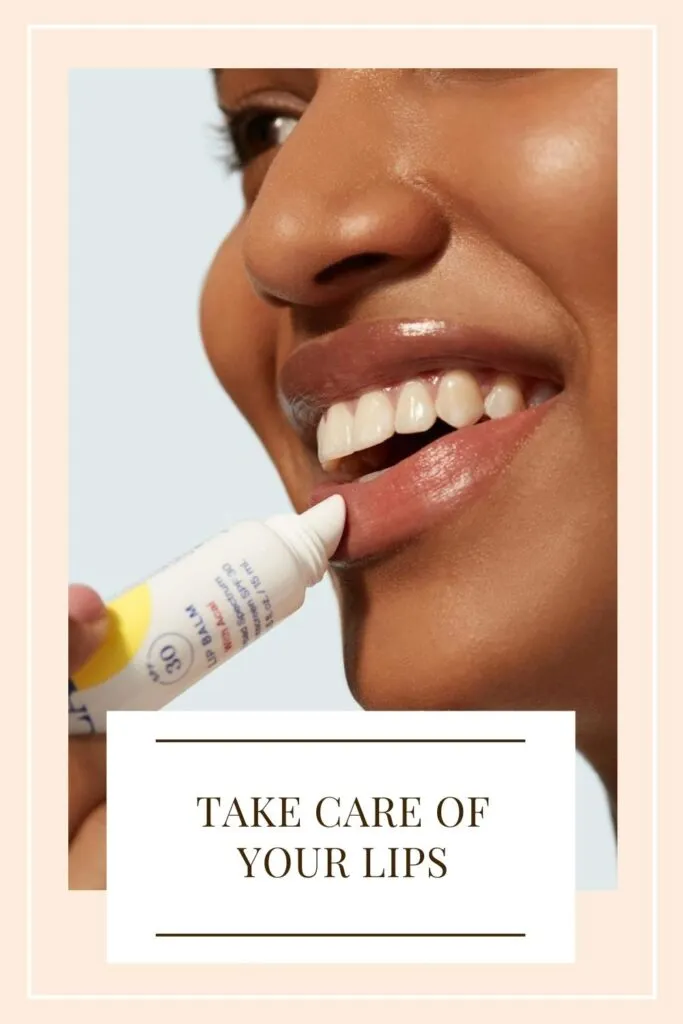 A girl is applying lip balm on her lips A girl is applying lip balm on her lips - skin care in winter