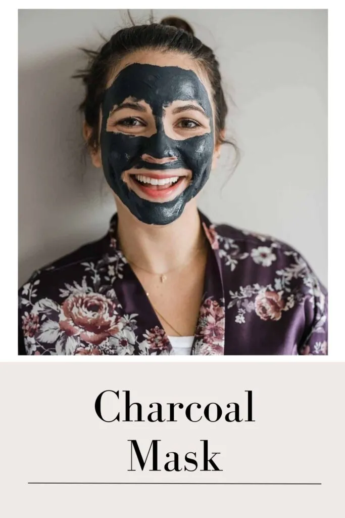 A smiling women in black floral dress on charcoal mask on her face A smiling women in black floral dress on charcoal mask on her face - skin blemishes