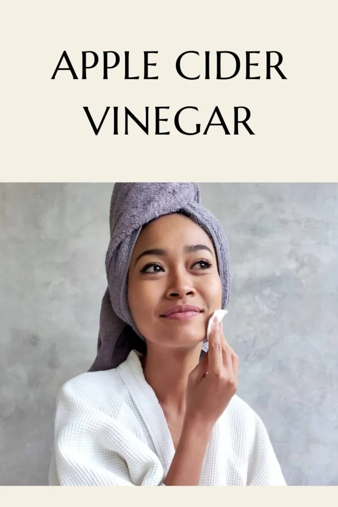 A girl in white bath robe applying apple cider vinegar on her face with cotton pad - - skincare routine for acne prone skin