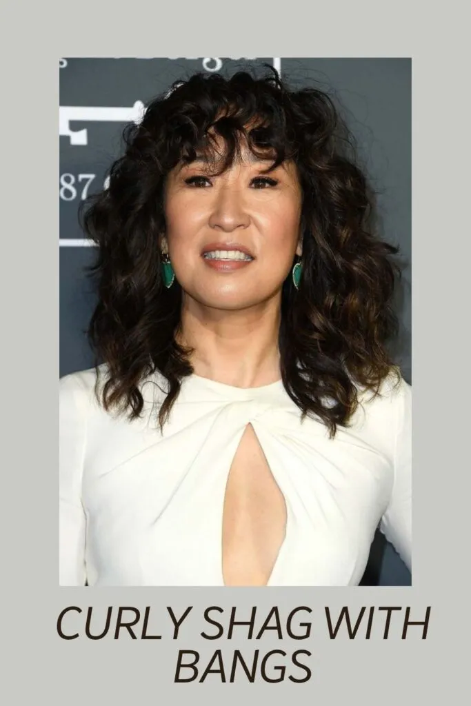 A women in white front open dress showing her Curly shag with bangs hairstyle A women in white front open dress showing her Curly shag with bangs hairstyle - hair color