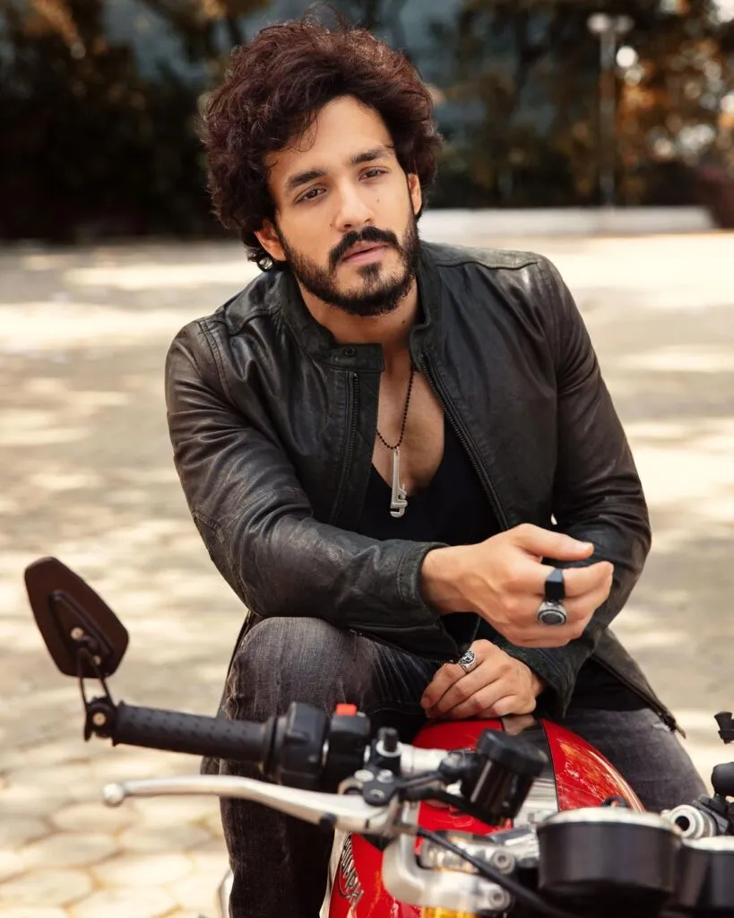 Akhil Akkineni in black leather jacket sitting on a bike and posing for camera Akhil Akkineni in black leather jacket sitting on a bike and posing for camera - most handsome actors of south indian industry