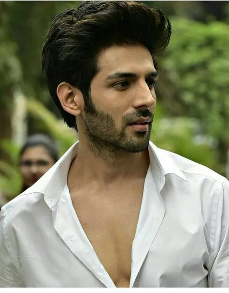 Kartik Aaryan in front open white shirt posing for camera and showing his quiff hairstyle Kartik Aaryan in front open white shirt posing for camera and showing his quiff hairstyle - Bollywood Actors Latest Hairstyles