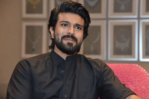 Ram Charan in black shirt sitting on a couch posing for camera Ram Charan in black shirt sitting on a couch posing for camera - top 10 south indian actors
