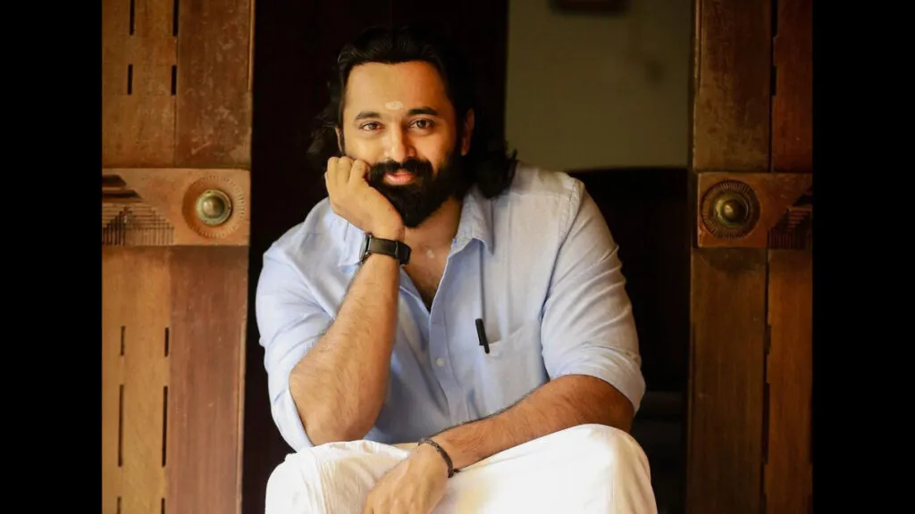 Smiling Unni Mukundan in traditional south indian dress sitting and posing for camera Smiling Unni Mukundan in traditional south indian dress sitting and posing for camera - most googled south indian actors 2020