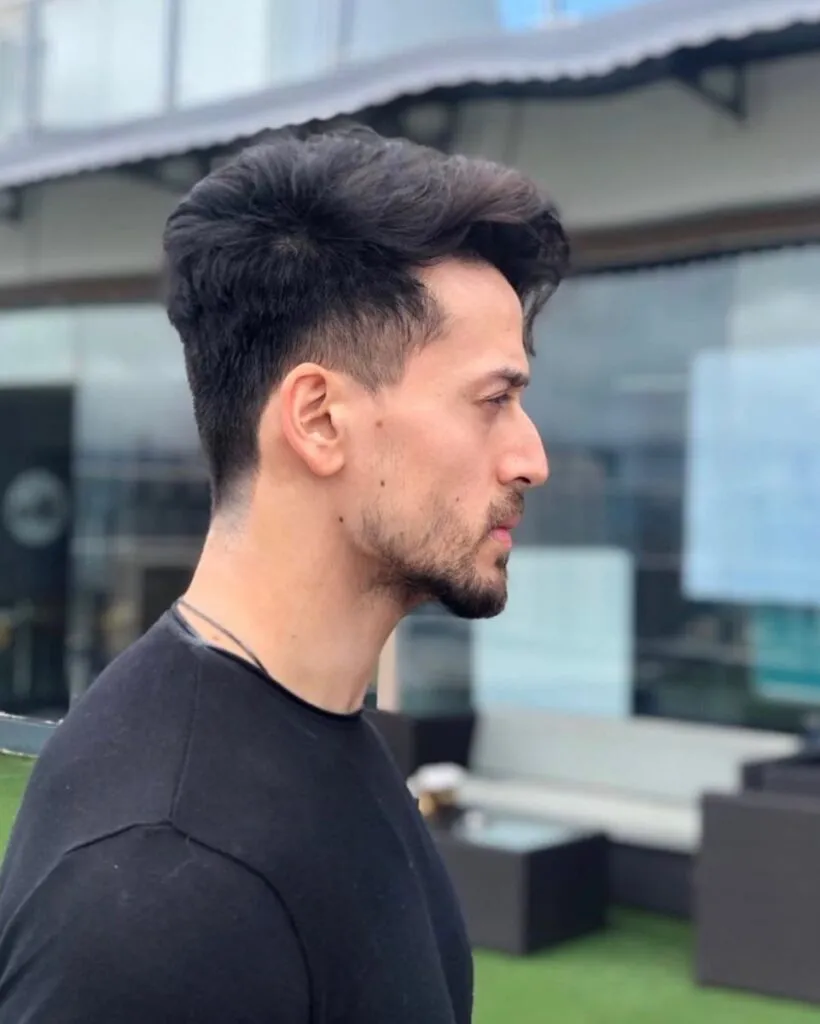 Tiger shroff in black t-shirt posing for camera and showing the side view of his hairstyle Tiger shroff in black t-shirt posing for camera and showing the side view of his hairstyle - indian actors hairstyles