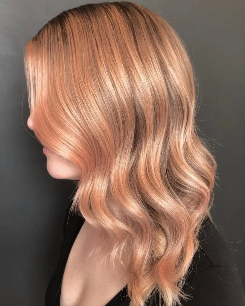 A girl in black round deep neck top showing the side view of her rose gold blonde hair color A girl in black round deep neck top showing the side view of her rose gold blonde hair color - long hair color