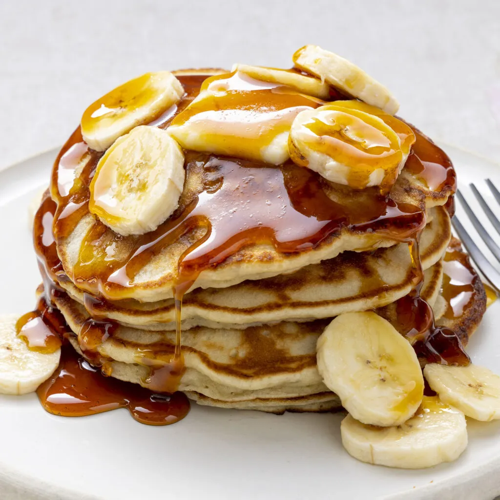 Banana Pancakes serving with honey and banana slices -breakfast ideas for muscle gain