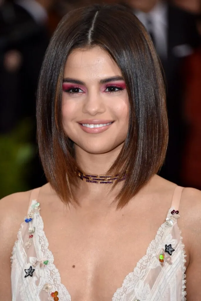Selena Gomez in white deep neck dress posing for camera and showing her Middle Part hairstyle Selena Gomez in white deep neck dress posing for camera and showing her Middle Part hairstyle - selena gomez short hair