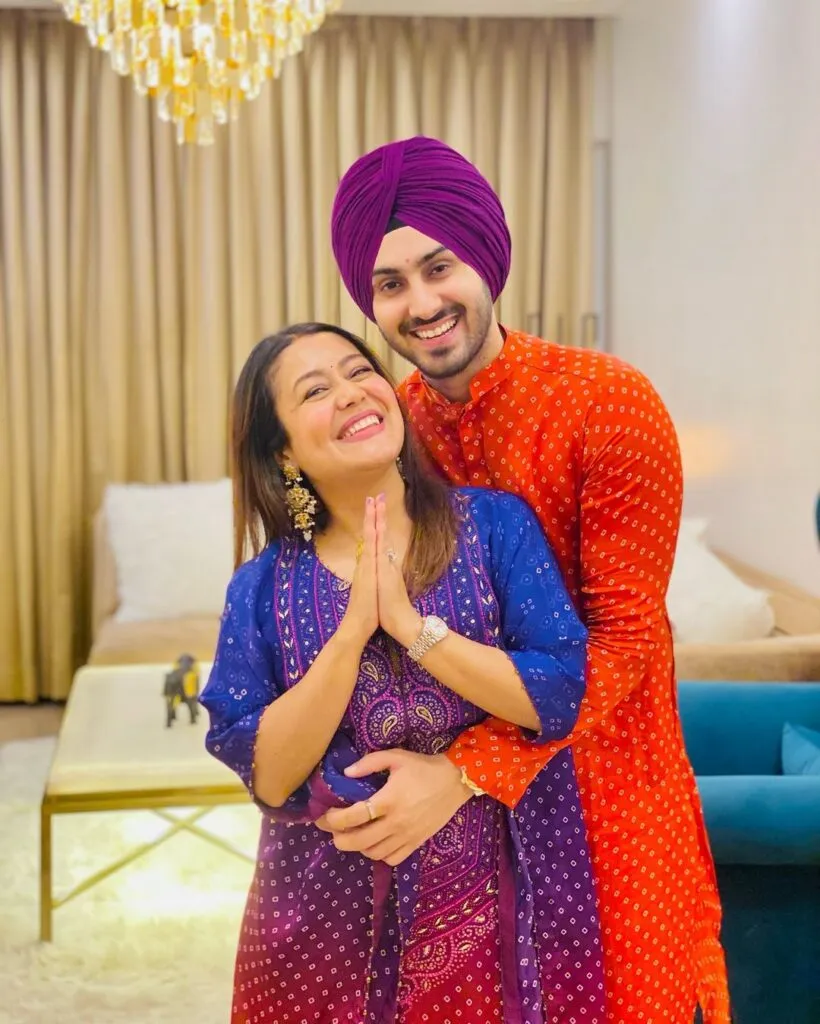 Neha Kakkar in blue suit with husband rohan preet singh in orange kurta posing for camera Neha Kakkar in blue suit with husband rohan preet singh in orange kurta posing for camera - hindi copule singers