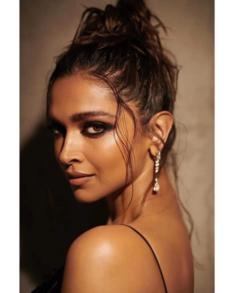 Deepika Padukone in black strappy dress and long earrings posing for camera and showing her High Volume Buns Deepika Padukone in black strappy dress and long earrings posing for camera and showing her High Volume Buns - Deepika padukone messy bun hairstyles