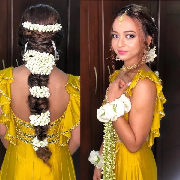 A girl in yellow deep neck dress poing for camera and showing her Multiple Loops of Gajras to Bdorn the braids A girl in yellow deep neck dress poing for camera and showing her Multiple Loops of Gajras to Bdorn the braids - Indian bridal hairstyles
