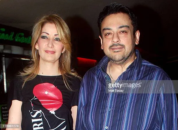 Adnan Sami in blue shirt with wife Roya Faryabi in black printed t-shirt posing for camera Adnan Sami in blue shirt with wife Roya Faryabi in black printed t-shirt posing for camera - Indian Singers