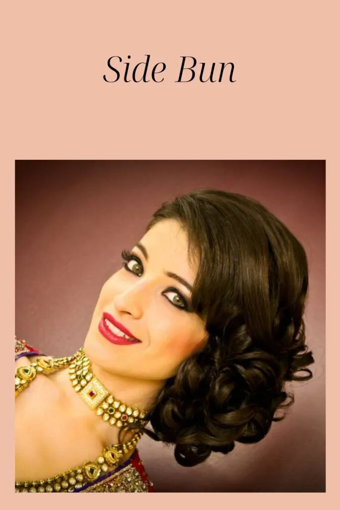 A women in traditional dress with matching jewellery and red lipstick showing the side view of her side bun A women in traditional dress with matching jewellery and red lipstick showing the side view of her side bun - Indian women hairstyle