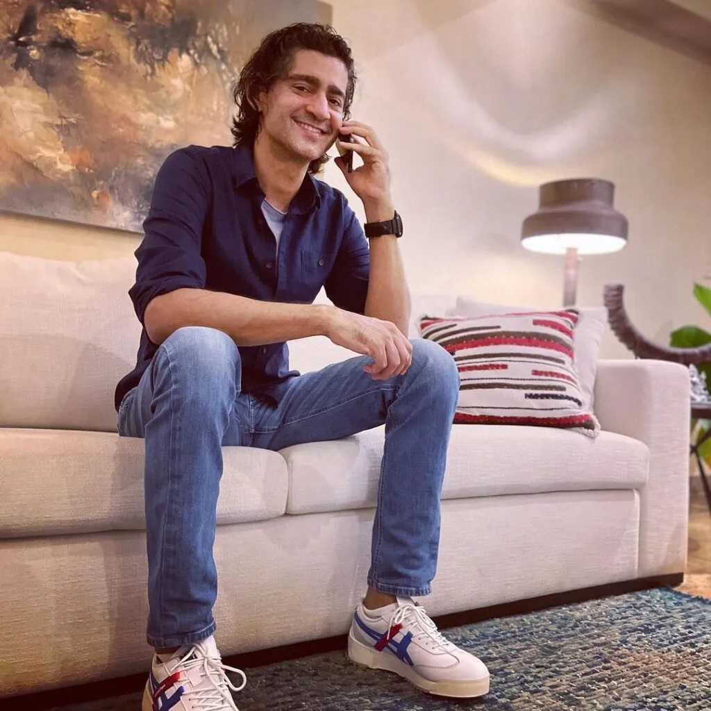 List of Famous Indian Celebrities (Personalities) with Diabetes & their Diet 4 Smiling Gaurav kapoor in black shirt with blue denim and white sports shoes taking over phone - indian celebrities with diabetes