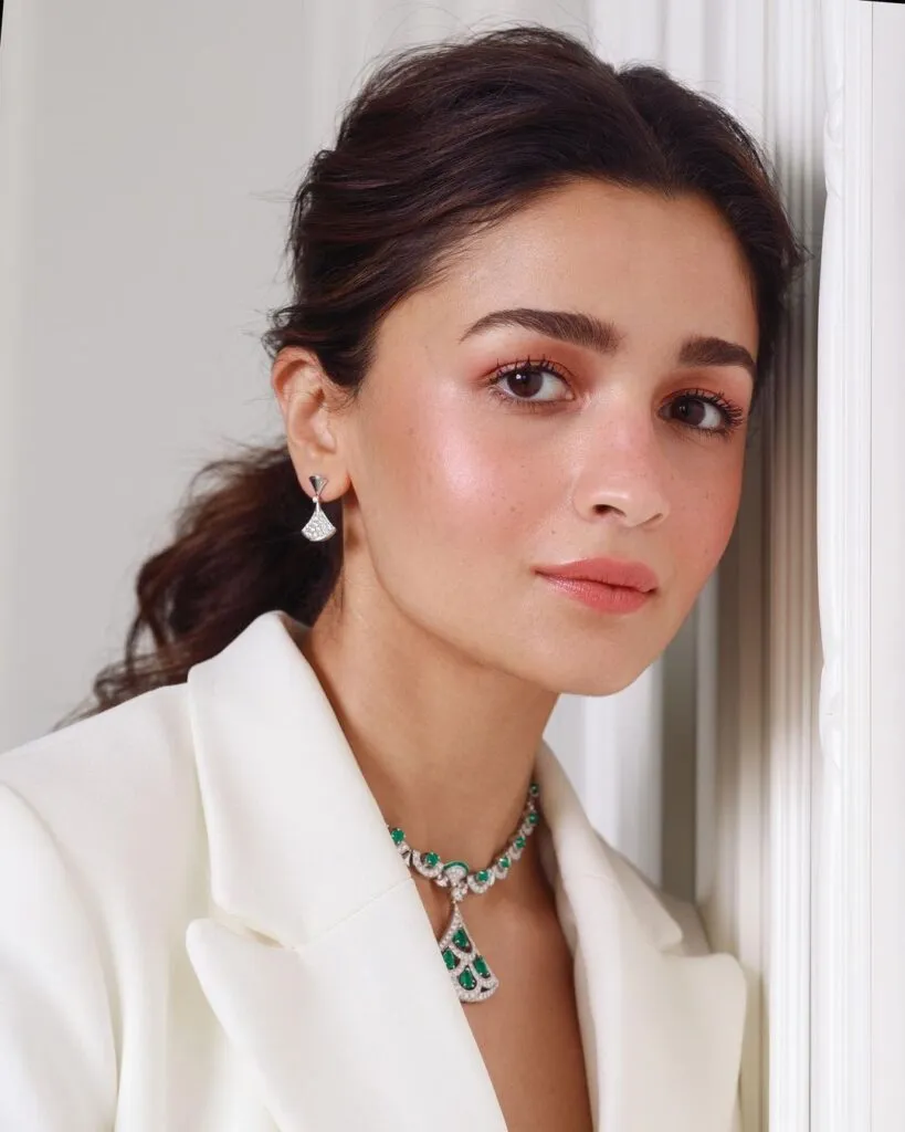 Alia Bhatt in white coat dress with green necklace and earrings posing for camera Alia Bhatt in white coat dress with green necklace and earrings posing for camera - Bollywood actresses hairstyles