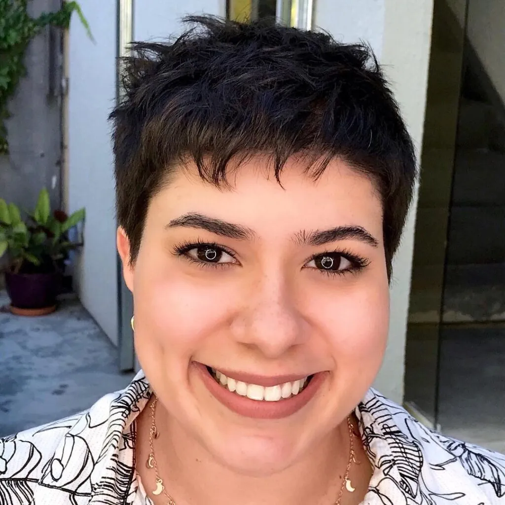 A smiling women in white and black printed shirt showing her Cropped Pixie haircut - best hairstyles for American Women