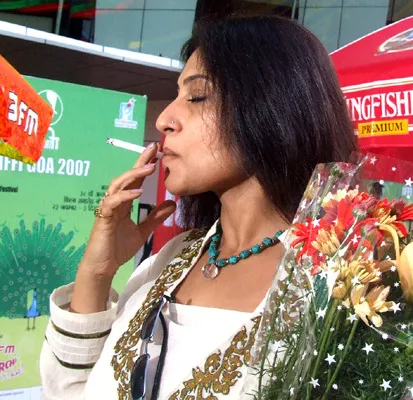 Rupa Ganguly in white and golden dress holding a buke and smoking - tv actress who smoke in real life