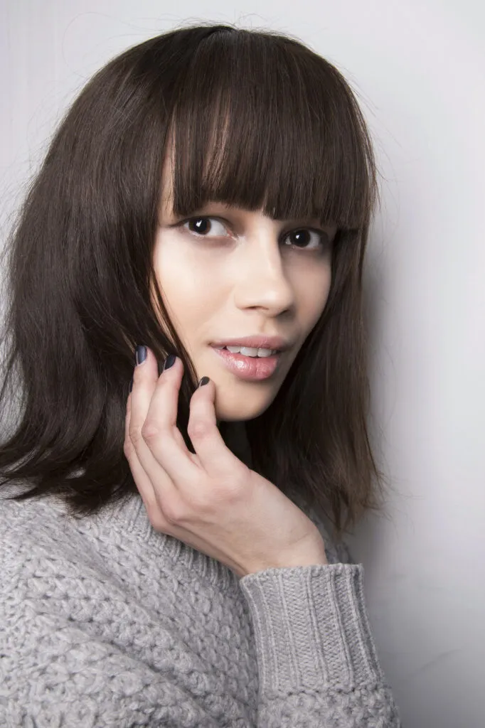 A woman in grey pullover and Thick Retro Bangs hairstyle A woman in grey pullover and Thick Retro Bangs hairstyle - hairstyles for medium hair for wedding