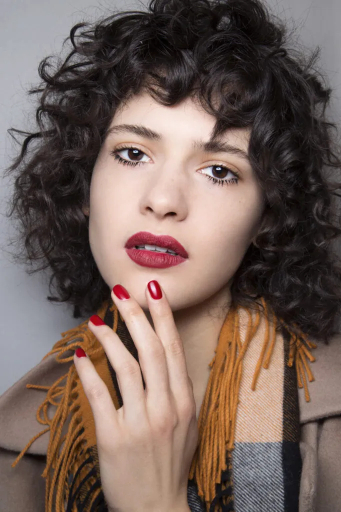 a girl in multicolor scarf with red lipstick and matching nail paint and Curly With Bangs hairstyle a girl in multicolor scarf with red lipstick and matching nail paint and Curly With Bangs hairstyle - daily hairstyles for medium hair