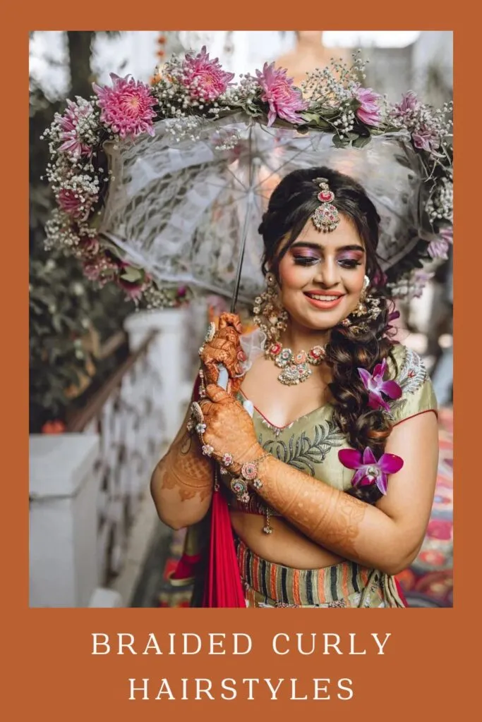 Woman in bridal look holding floral umbrella with Braided Curly Hairstyle Woman in bridal look holding floral umbrella with Braided Curly Hairstyle - Curly Hairstyles for lehenga