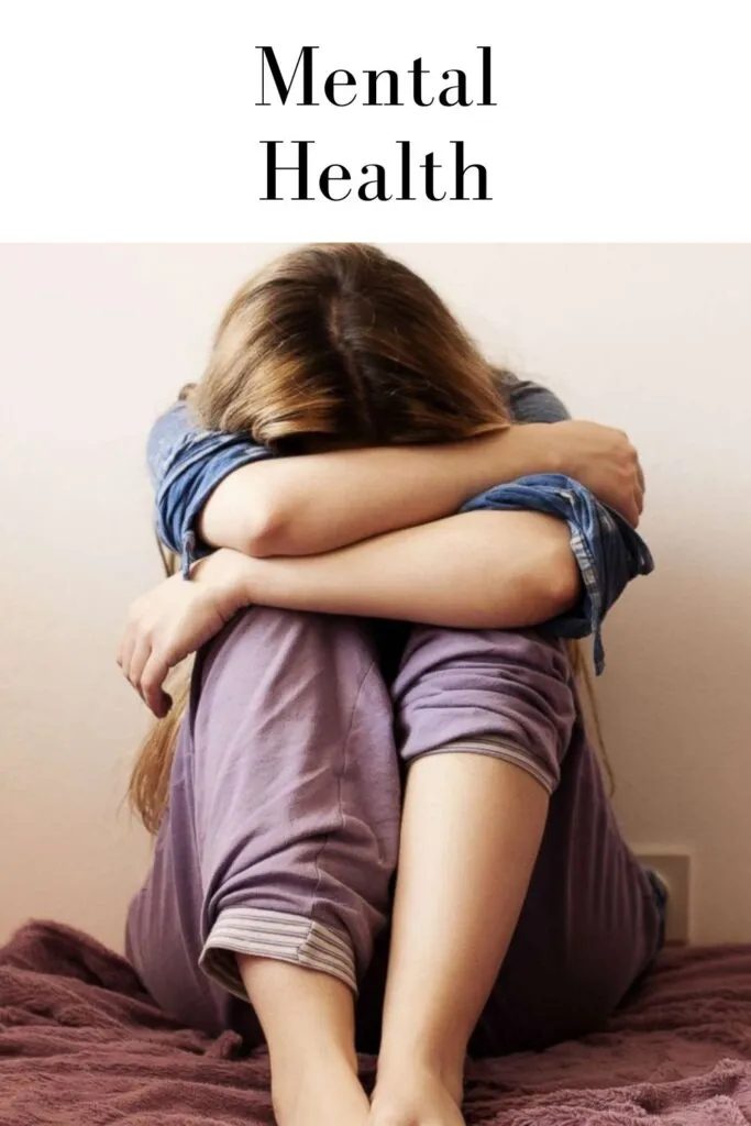A woman in sitting on a couch wrapping arms around her head A woman in sitting on a couch wrapping arms around her head - mental health